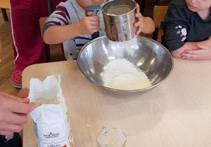 Dziecko przesiewa mąkę